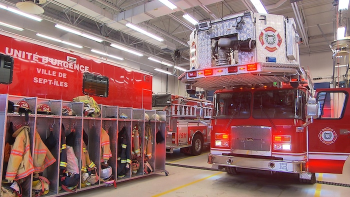 Camions et équipements de pompiers, notamment casiers avec les casques et habits, à l'intérieur de la caserne à Sept-Îles.