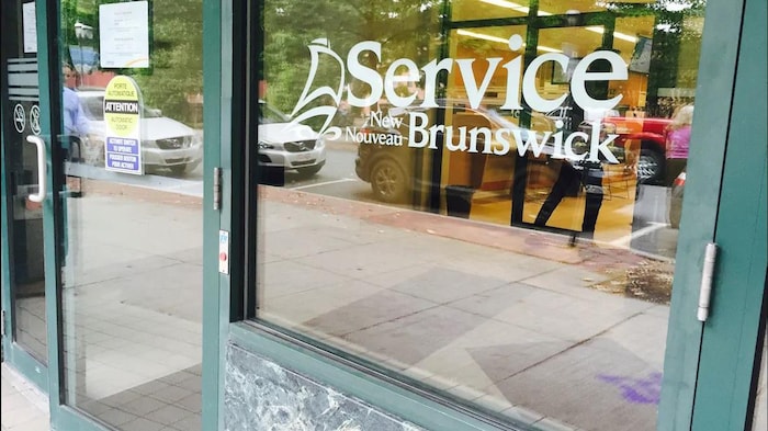 Le logo de Service Nouveau-Brunswick dans une fenêtre de leur bureau. 