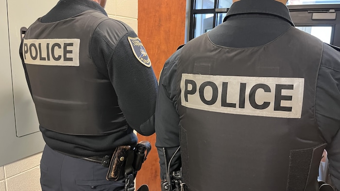 Des policiers de dos en uniforme.