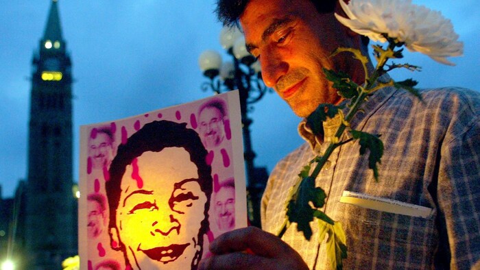 Shahpour Rahanam participe à une veillée aux chandelles en hommage à la photojournaliste Zahra Kazemi et tient son portrait dans ses mains.