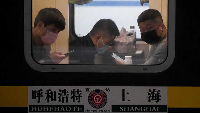 Des passagers dans un train portant un masque. 