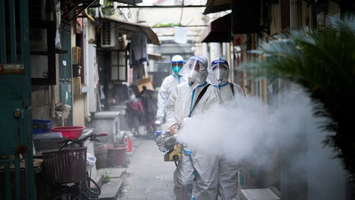 Des travailleurs en habits de protection désinfectent un quartier de Shanghai. 