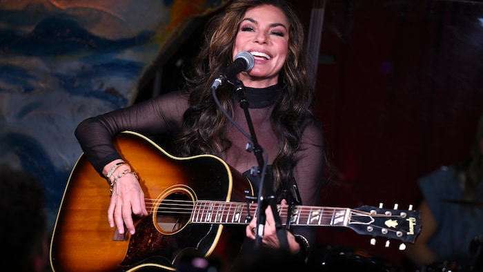 Shania Twain tenant une guitare.