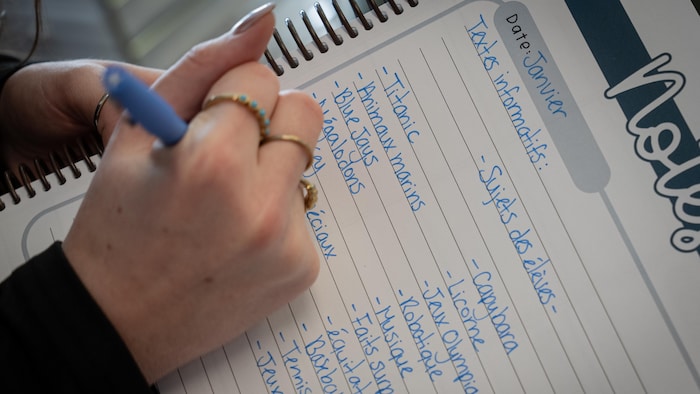 Une main écrit des informations sur un papier.