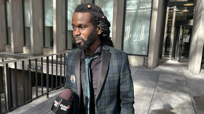 Un homme répond aux questions de la presse.