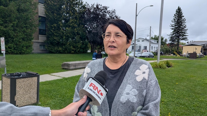 Sharon Hunter se fait interviewer par un journaliste de RNC Média devant le palais de justice.
