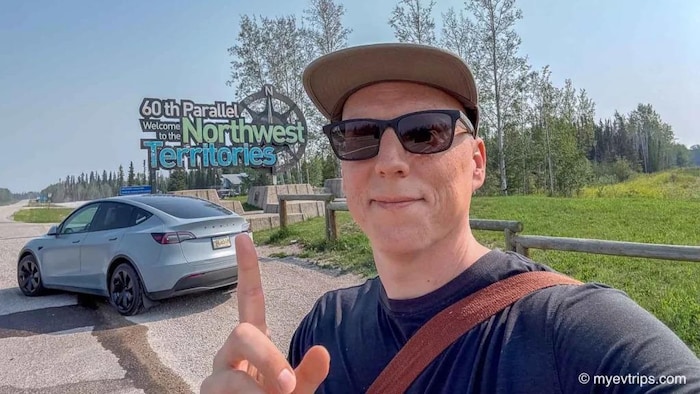 Un portrait de Shaun Robertson devant un panneau d'accueil des Territoires du Nord-Ouest.
