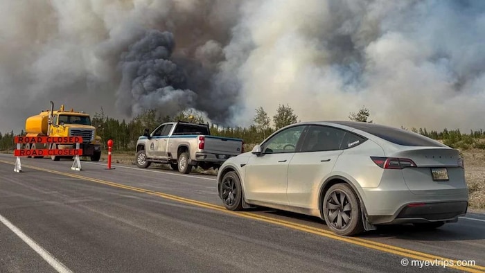 Un véhicule électrique est mis de l’avant, avec une panache de fumée en arrière-plan.