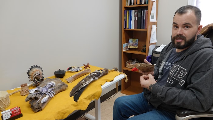 Shawn Francis est assis devant des objets culturels.