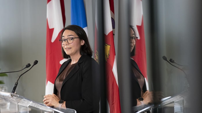 Une femme devant un lutrin, en conférence de presse.