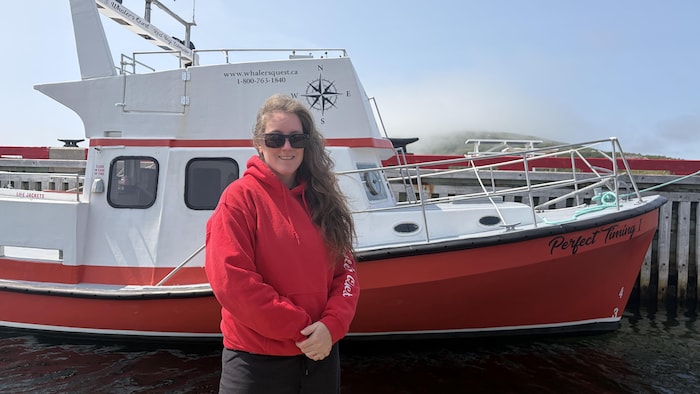 Sheena Fowler debout sur le quai devant un bateau rouge et blanc.