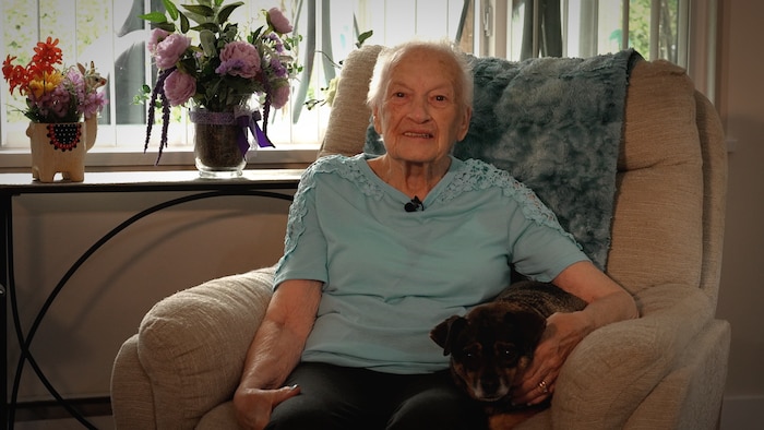 Une femme assise dans sa maison avec un chien.