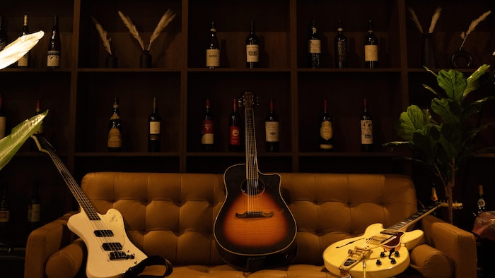 Des guitares posées sur un canapé installé devant une étagère.