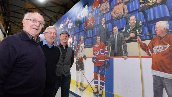 Jean Perrault, Ivan Beaulieu et Serge Malenfant sourient devant la murale.