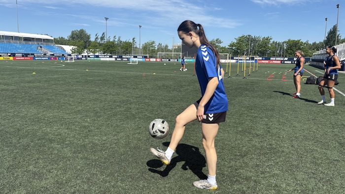 Elle drible avec un ballon de soccer sur le terrain des Roses de Montréal.