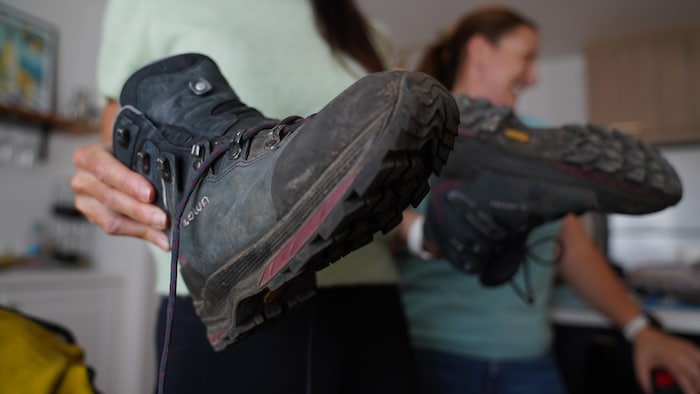 Marie-Ève tient ses bottes de randonnée dans ses mains.
