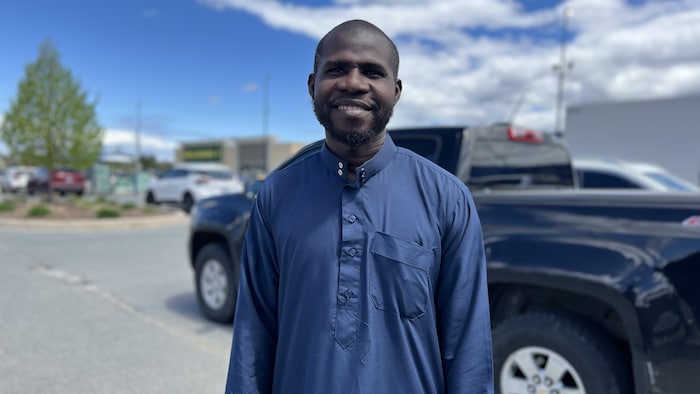 Portrait de Sherif Olayemi dans le stationnement d'un centre d'achat.
