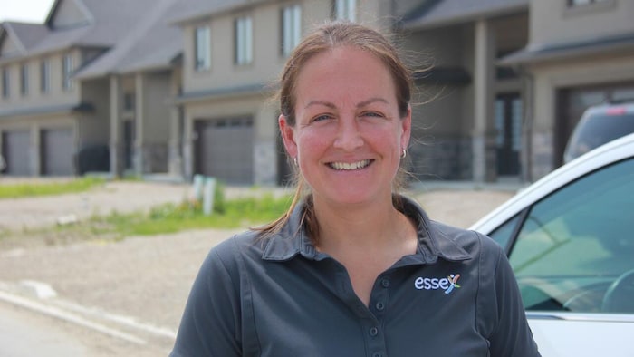 Sherry Bondy souriante pose devant des maisons en rangée.