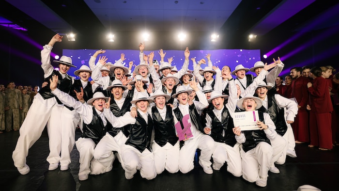 Des danseurs costumés célèbrent un prix sur une scène. 