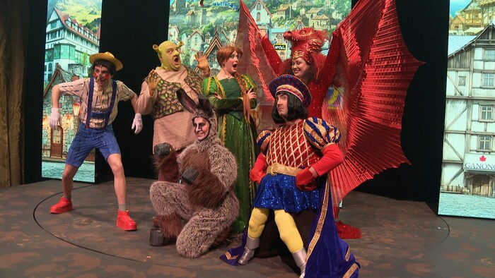 Des comédiens sur scène déguisés en Pinocchio, Shrek, un âne, une princesse, un dragon et un lord tyrannique.