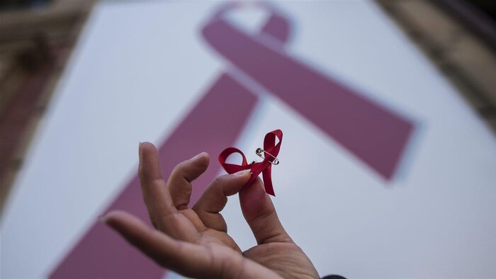 Une femme tient dans ses mains le ruban rouge qui est devenu le symbole de la lutte contre le sida.
