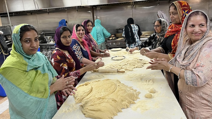 Des femmes en tenue traditionnelle préparent du pain.