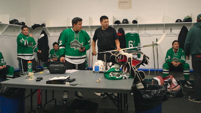 L'homme pied-noir montre des hommes dans un vestiaire de hockey.