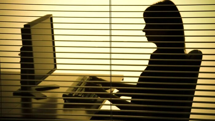 Silhouette d'une femme assise à un bureau.