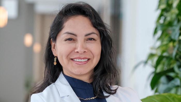 Dr Silma Solórzano porte une blouse de médecin. Elle se tient debout, les bras croisés.