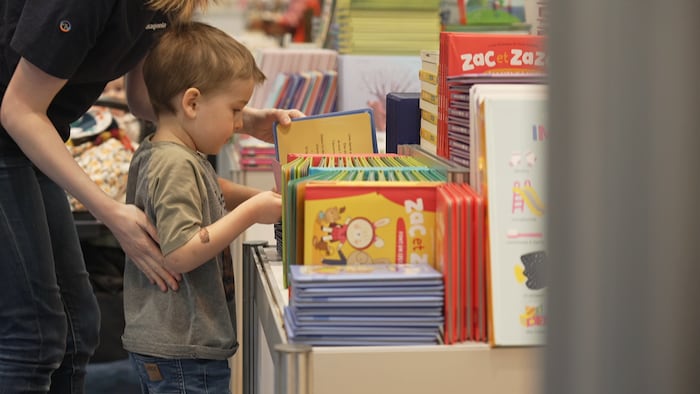 Un enfant regarde un livre coloré. 