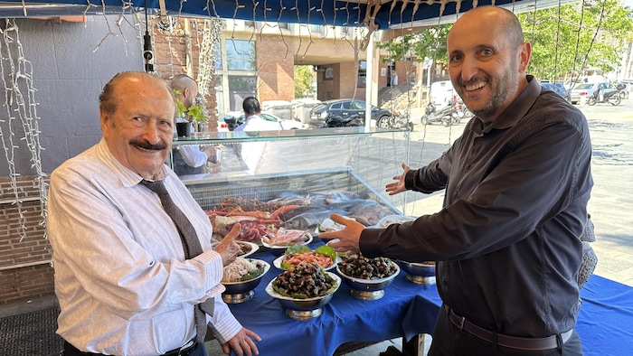 Deux restaurateurs devant un étalage de poissons.