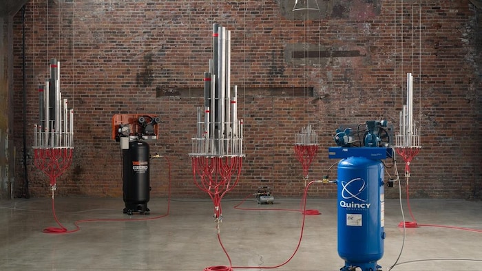 Un orgue d'église rescapé est raccordé à des compresseurs d'air industriels. L'air insufflé artificiellement force l'instrument à libérer de longs soupirs physiques, transformant le bruit métallique des machines en cris musicaux éthérés. 