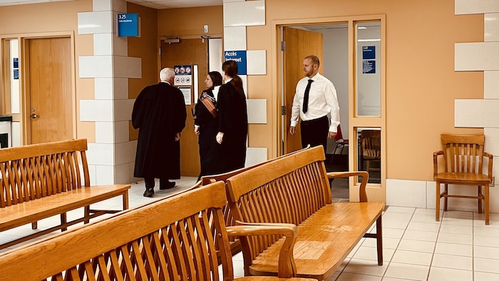 Simon Carrier et ses avocats Benoit Ducharme et Claude Baillargeon entrent dans la salle d'audience gardée par un constable spécial.
