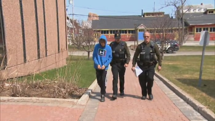 Simon Dufort-Chouinard accompagné de deux policiers de la Sûreté du Québec.