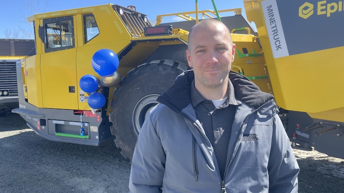 Simon Fontaine, debout, sourit à la caméra devant un camion minier.