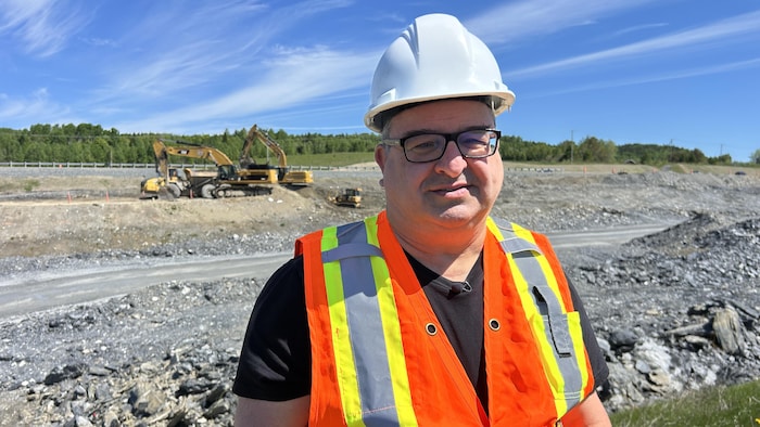 Simon Lavoie porte un casque de construction et une veste orange dans un chantier.