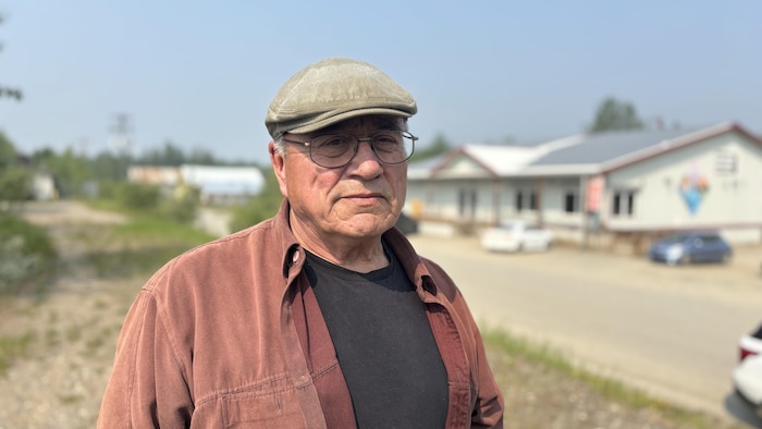 Un homme à l'extérieur avec un magasin général en arrière-plan.