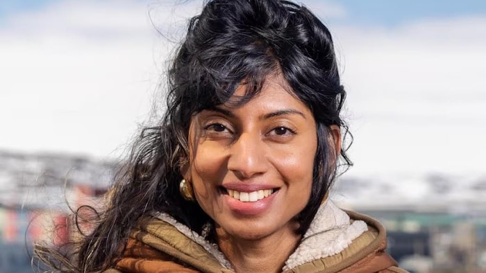 Une femme chaudement vêtue qui sourit.