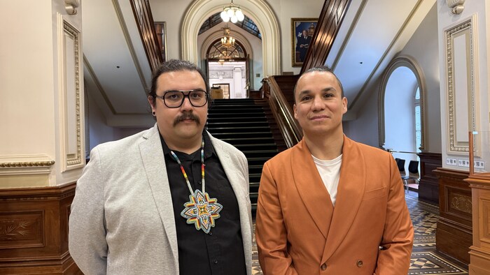 Deux hommes posant devant les marches d'escalier à l'Assemblée nationale. 