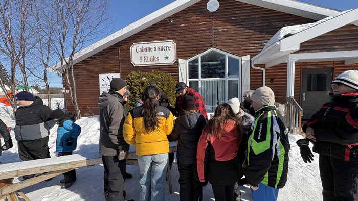 Une troupe rassemblée autour de la Cabane à sucre 5 étoiles pour tester le sirop d'érable.