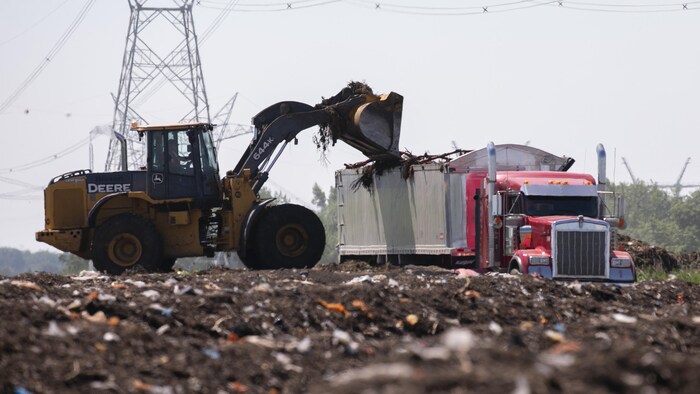 Une pelle mécanique ajoute des déchets dans un camion.