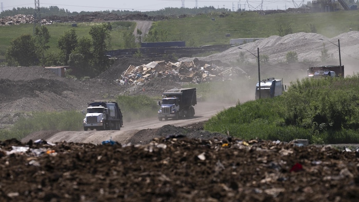 Quatre camions d'ordures sur un site d'enfouissement.