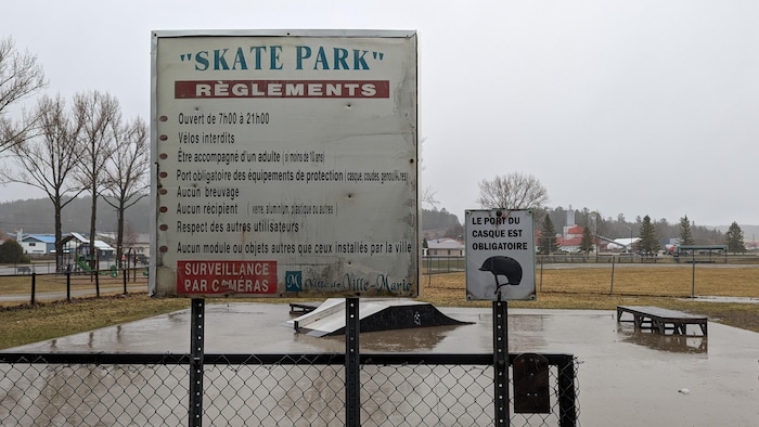 Un skatepark et une pancarte énonçant les règlements.