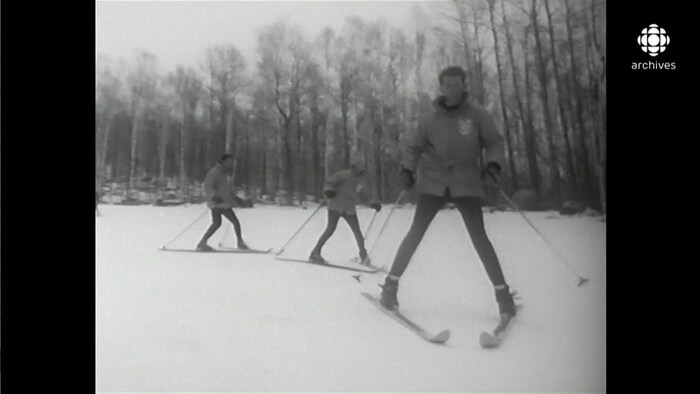 Trois skieurs se suivant en file sur une piste, les skis en pointe de tarte.