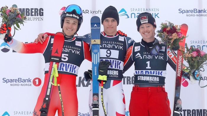 Trois skieurs posent ensemble sur un podium.