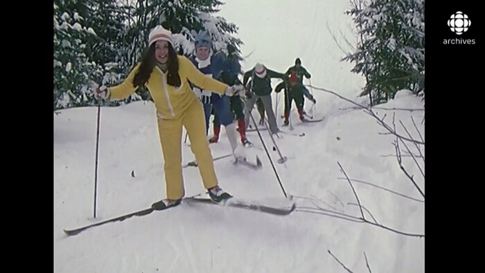 Groupe de skieurs qui monte une pente enneigée. 