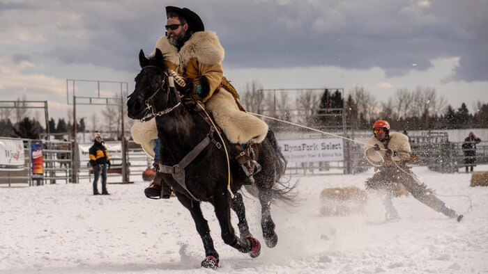 Un cavalier sur son cheval tire un skieur.