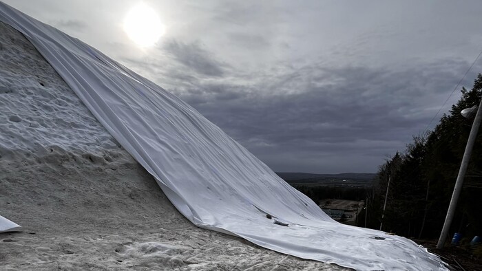 Une butte de neige partiellement recouverte d'une couverture isolante.
