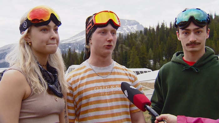 Trois jeunes portant des lunettes de ski sur la tête. 