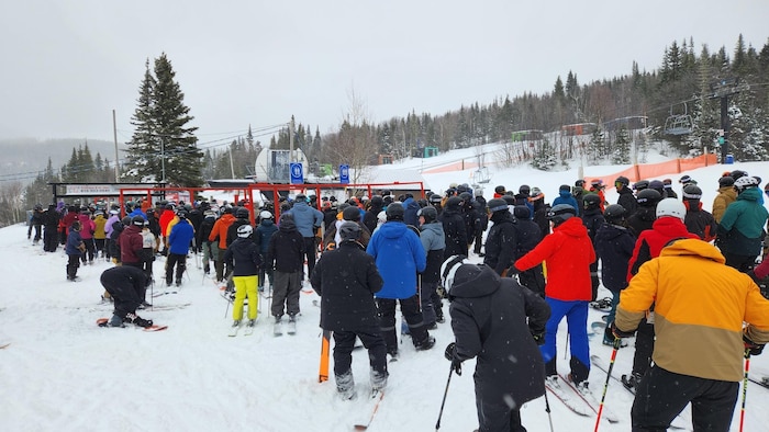 Des skieurs sont en rang dans une pente de ski.